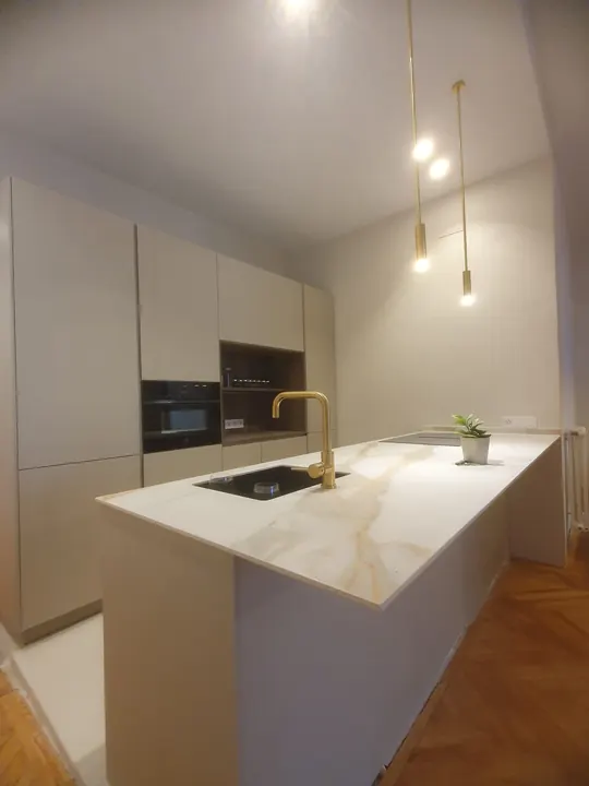 Cocina con isla de porcelánico veteado y parquet en espiga